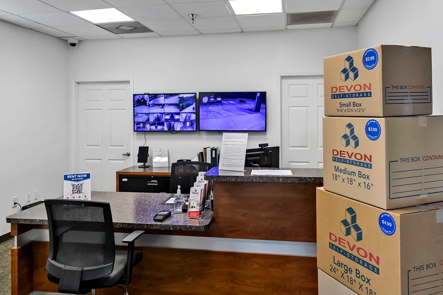 Self storage office with customer service desk, security camera monitors, and moving boxes